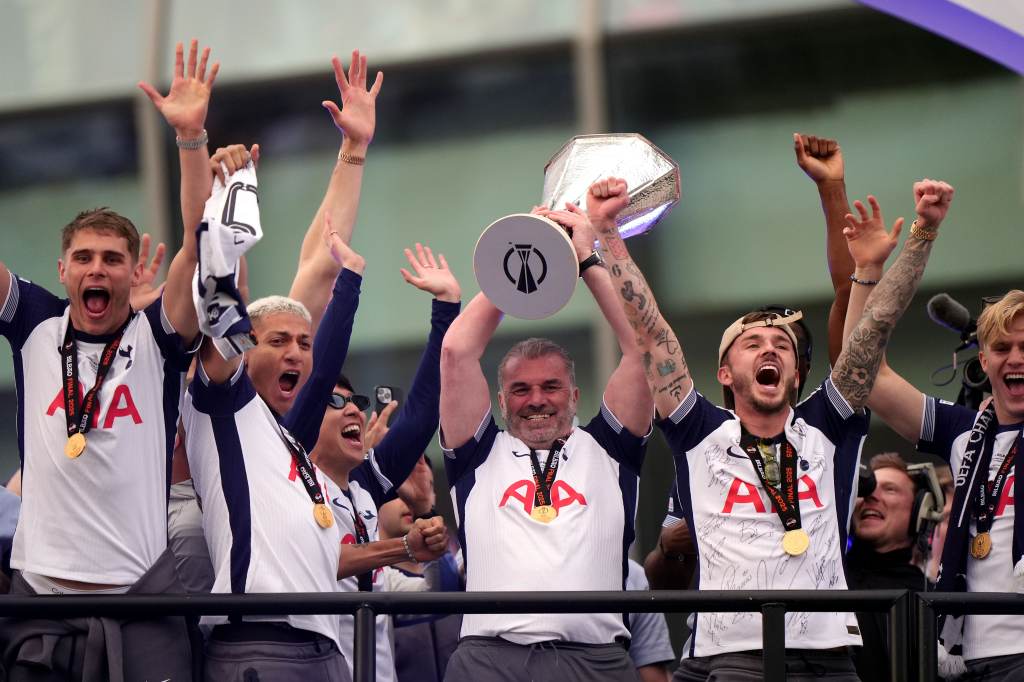 Celebración del equipo de fútbol Tottenham Hotspur levantando un trofeo tras ganar un campeonato, con jugadores mostrando alegría y entusiasmo.